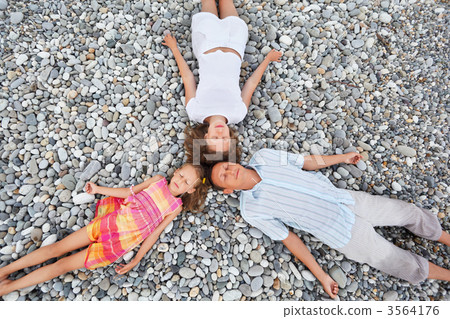 Happy family with little girl lying on stony beach, closed eyes, 3564176