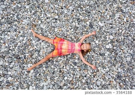 little girl lying on stones on stone seacoast 3564188