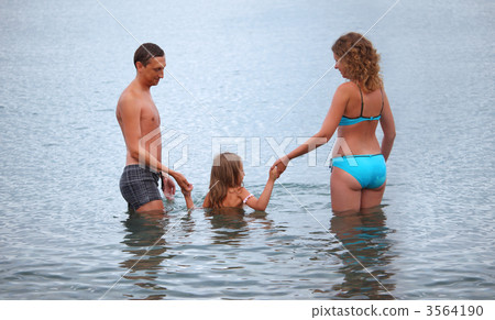 Happy family with little girl bathe in sea, standing back 3564190