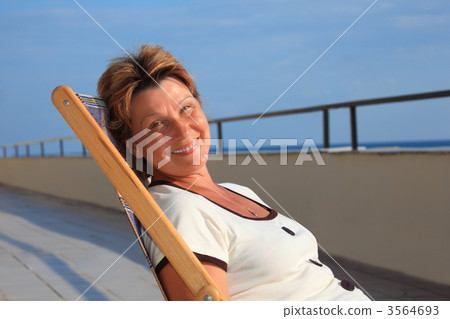 middleaged woman in lounge on veranda over sea 3564693
