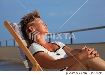 dreaming middleaged woman in lounge on veranda over sea dreaming middleaged woman in lounge on veranda over sea 3564694