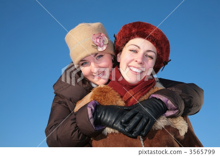 young woman embraces other against blue sky in winter 3565799