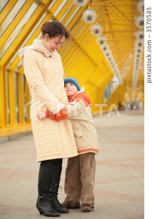 son embraces mother on footbridge 3570585
