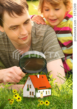 father with little girl looking on small house through magnifier father with little girl looking on small house through magnifier 3571209