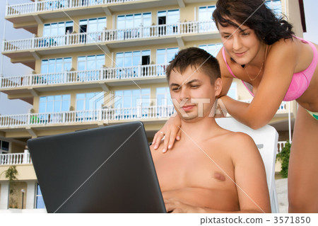 pretty woman and young man reclining on chaise lounges on beach 3571850