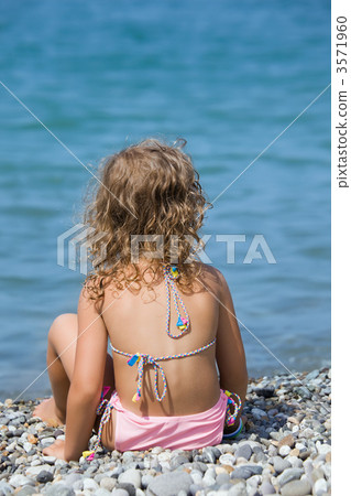 pretty little girl sitting on stone seacoas, sitting by back pretty little girl sitting on stone seacoas, sitting by back 3571960