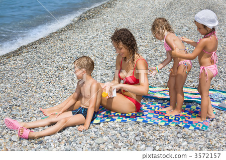 young woman and three children smear each other backs with cream young woman and three children smear each other backs with cream 3572157