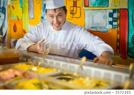 cheerful cook in uniform near counter with meal 3572165