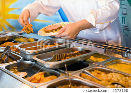 Hands of cook putting in plate vegetable ragout in public cateri 3572168