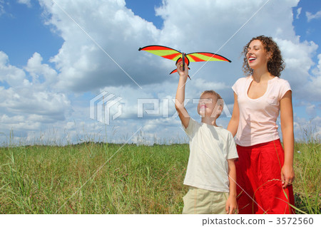 young woman and boy plays kite on meadow 3572560