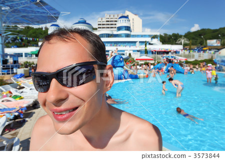 smiling young man in sunglasses in aquapark, wide angle 3573844