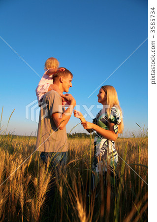 Mother and father with child on shoulders on wheaten field Mother and father with child on shoulders on wheaten field 3585734