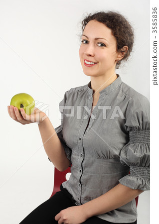 young attractive woman holding an apple in one hand, looking at young attractive woman holding an apple in one hand, looking at 3585836
