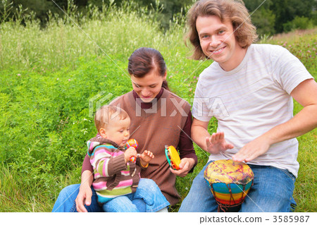 Parents and baby on nature with musical instruments 3585987
