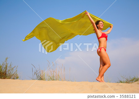 Young girl on sand with yellow shawl in hands Young girl on sand with yellow shawl in hands 3588121