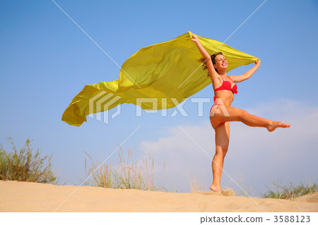 Young girl on sand with yellow shawl in hands Young girl on sand with yellow shawl in hands 3588123