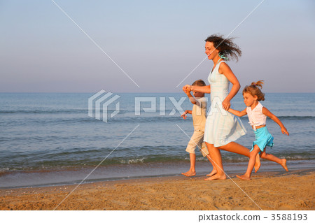 Mother with children running on edge of sea 3588193