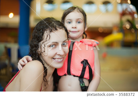 Smiling beautiful woman and little girl  in lifejacket after swi 3588372