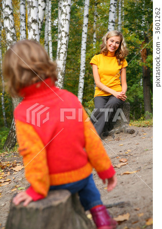 Mother with child sit on stubs in wood in  autumn. 3601262