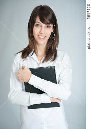 Smiling brunette in white shirt holding a black book 3617128