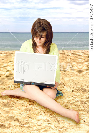 casual girl using a laptop on the beach 3725427