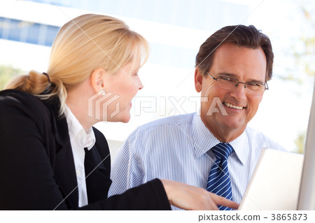 Businessman and Female Colleague Using Loptop Outdoors Businessman and Female Colleague Using Loptop Outdoors 3865873