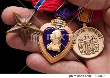 Man Holding Purple Heart, Bronze and National Defense War Medals Man Holding Purple Heart, Bronze and National Defense War Medals 3868359