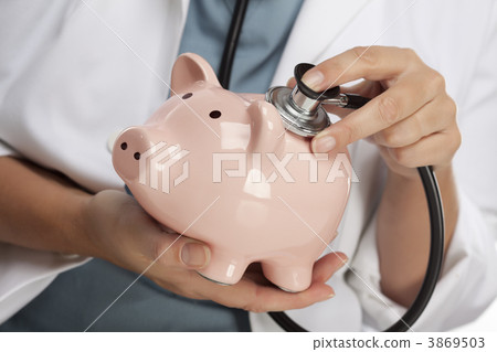 Doctor Holding Stethoscope to Piggy Bank Doctor Holding Stethoscope to Piggy Bank 3869503