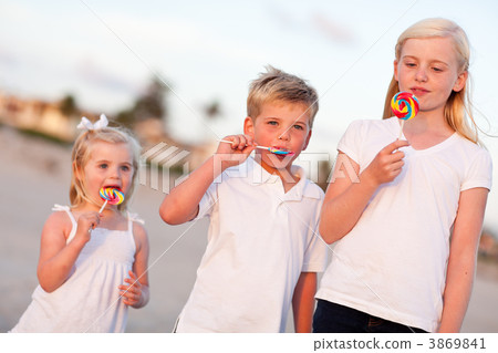 Cute Brother and Sisters Enjoying Their Lollipops Outside 3869841