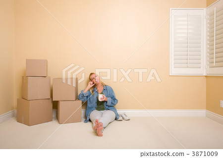 Happy Woman Relaxing Next to Boxes on Floor with Cup Happy Woman Relaxing Next to Boxes on Floor with Cup 3871009