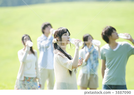 Young people drinking water in the meadow 3887090