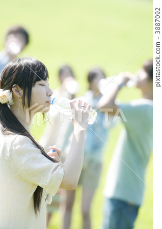 Young people drinking water in the meadow 3887092