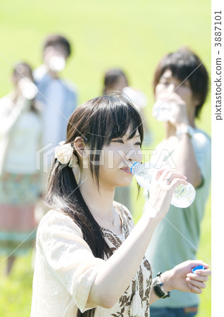 Young people drinking water in the meadow 3887101