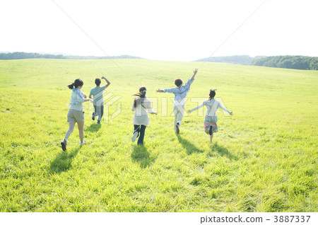 The rear view of the young people running in the meadow The rear view of the young people running in the meadow 3887337