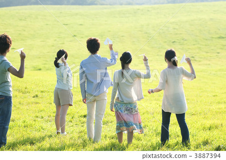 Young people who fly paper airplanes in the meadow Young people who fly paper airplanes in the meadow 3887394