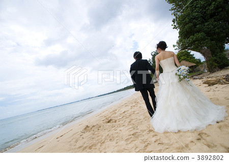 Bride and groom walking on the beach 3892802