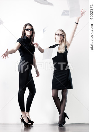Two young businesswomen throwing out paper Two young businesswomen throwing out paper 4002571