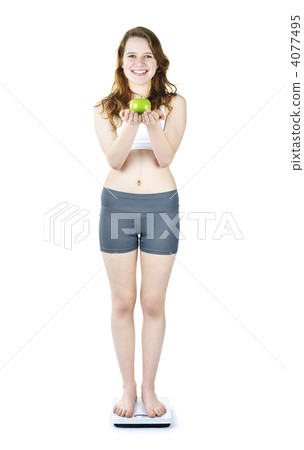 Young smiling girl on bathroom scale holding apple Young smiling girl on bathroom scale holding apple 4077495