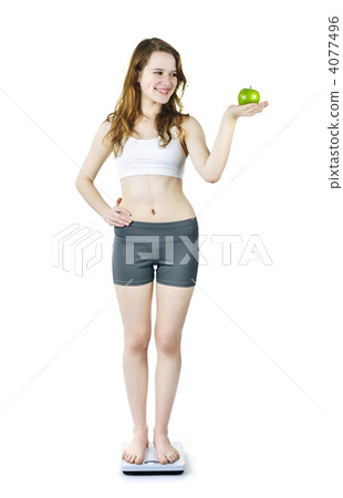 Young smiling girl on bathroom scale holding apple Young smiling girl on bathroom scale holding apple 4077496