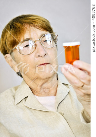 Elderly woman reading pill bottles 4093768