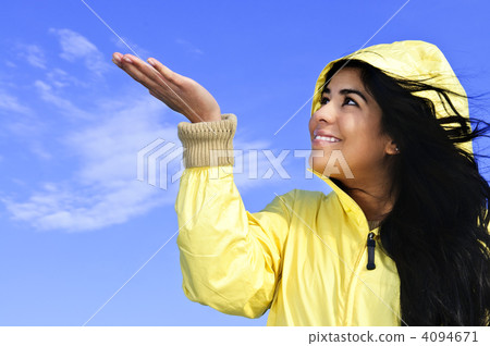 Beautiful young woman in raincoat checking for rain Beautiful young woman in raincoat checking for rain 4094671