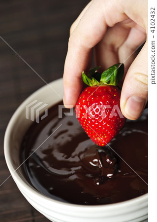 Hand dipping strawberry in chocolate Hand dipping strawberry in chocolate 4102432