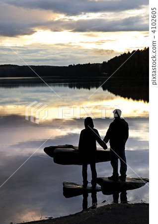 Silhouette of people watching sunset at lake 4102605