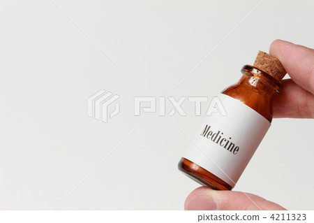 Hand holding a small bottle of "Medicine" 4211323