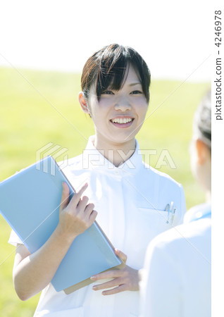 A nurse smiling with a file in the meadow 4246978