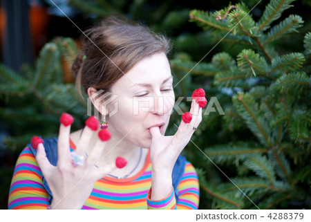 Beautiful young girl in bright clothes eating raspberries 4288379