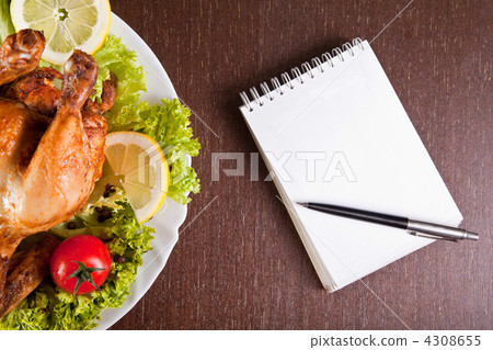 Restaurant table with roast chicken, notebook and pen 4308655