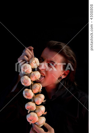 Evil vampire with scary eyes is licking garlic 4308808