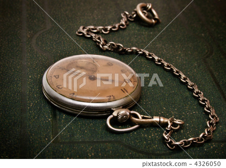 Old clock with chain lying on rough green surface 4326050