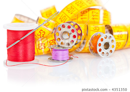 Colored bobbins for sewing and measuring tape over white backgro Colored bobbins for sewing and measuring tape over white backgro 4351350
